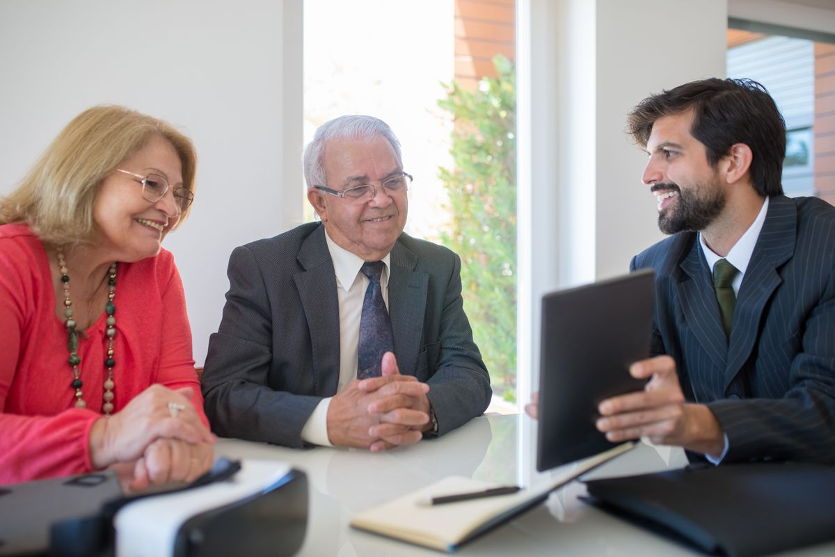 An advisor presenting figures on a tablet to a couple in a bright office