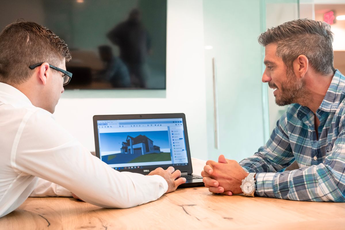 An engineer and client reviewing a 3D building model on a laptop at a conference table